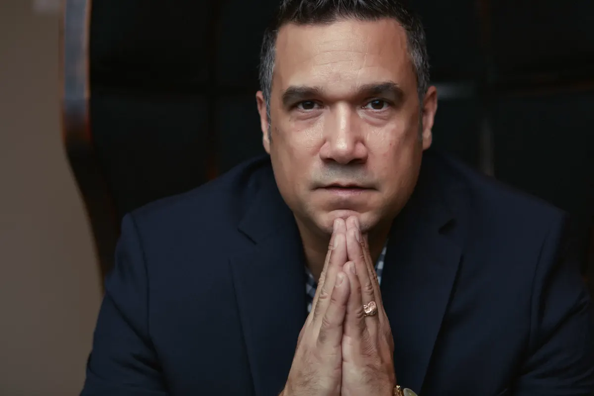 Ted Canto seated in a navy jacket and listening thoughtfully
